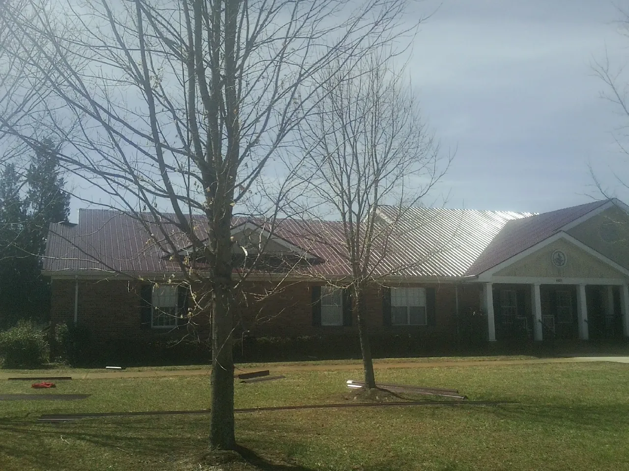 Red metal roof on a brick building seen from the front lawn in Fonda