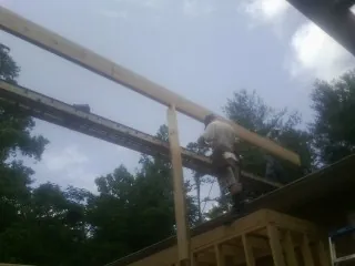 Carpenter setting a ridge beam over a new addition frame — Ice Dam Removal by Roofing Brothers in Fonda