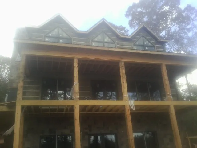 Dormers and porch framing on a large log home under construction — Roof Coating work by our crew in Fonda