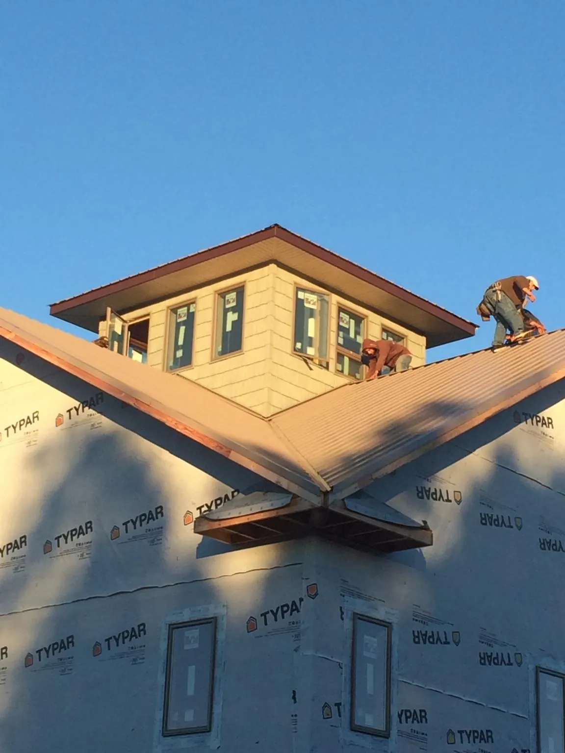 Roofers working around a rooftop cupola on a new metal roof at sunset — Roof Waterproofing in Fonda by Roofing Brothers